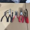 A 7-piece automotive pliers set laid out flat on cardboard, featuring red and black handles and various precision jaws.