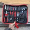 An overhead view of the 11-piece deluxe auto repair kit featuring pure red handle pliers, nylon trim removal tools, and electrical terminal extractors in a zippered case.