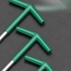 T-handle spark plug wrench with green handle and silver spring guard, displayed diagonally on a dark background.